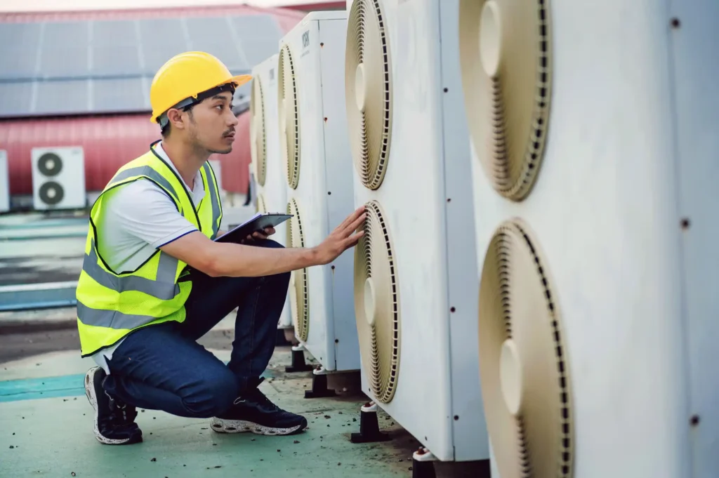 HVAC technician in safety gear inspecting commercial air conditioning units, emphasizing expert maintenance services for efficient heating and cooling in Gilbert, AZ.